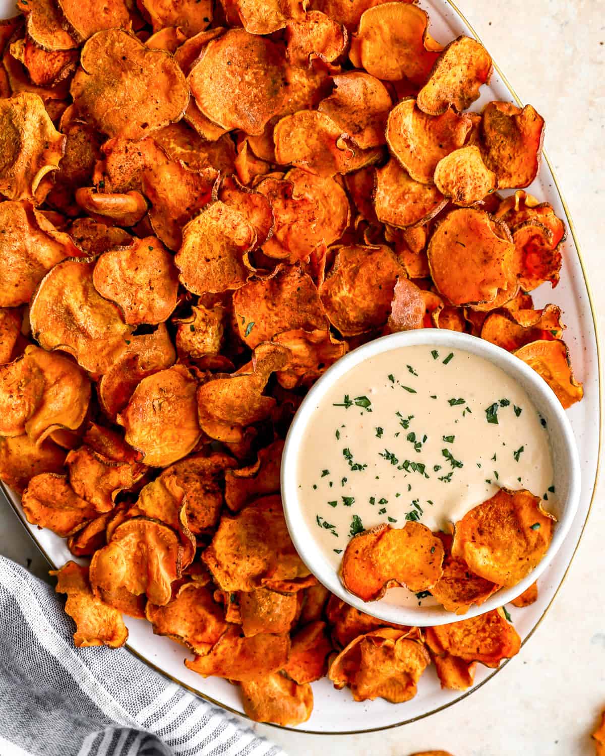 overhead view of baked sweet potato chips on a platter with dipping sauce.