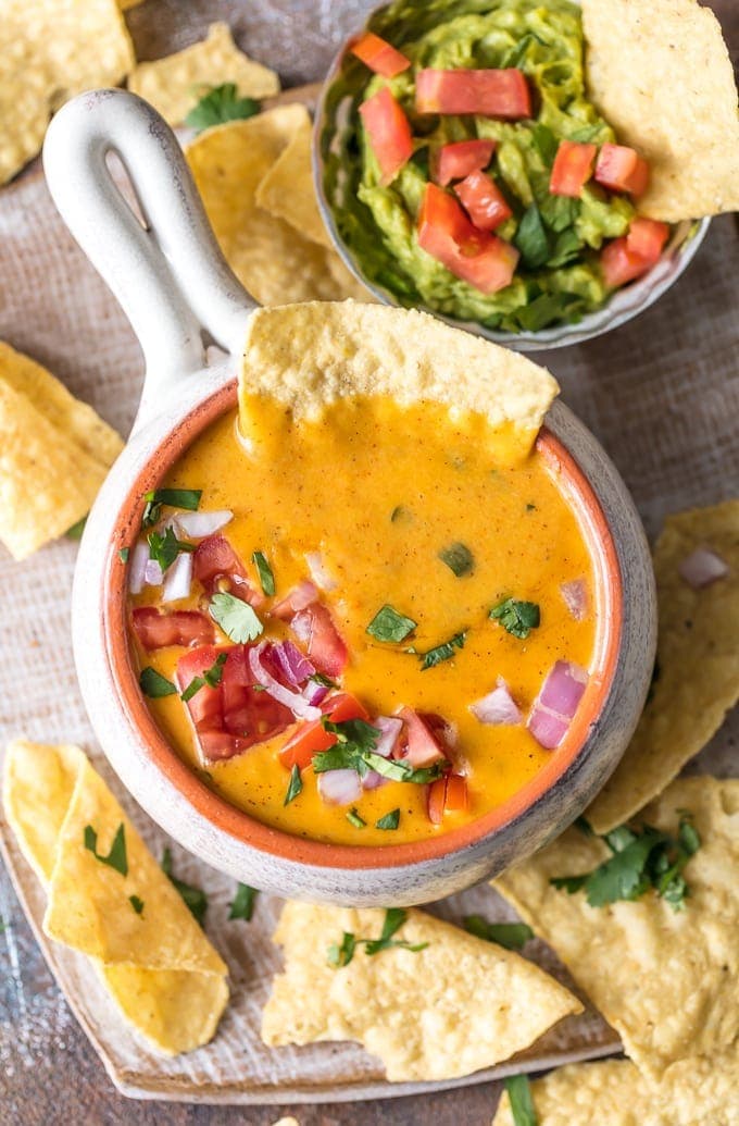 queso dip and guacamole on a plate with chips