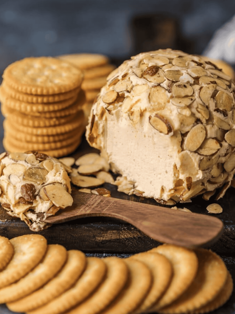 A delicious cheese ball recipe with almonds and crackers elegantly displayed on a wooden board.