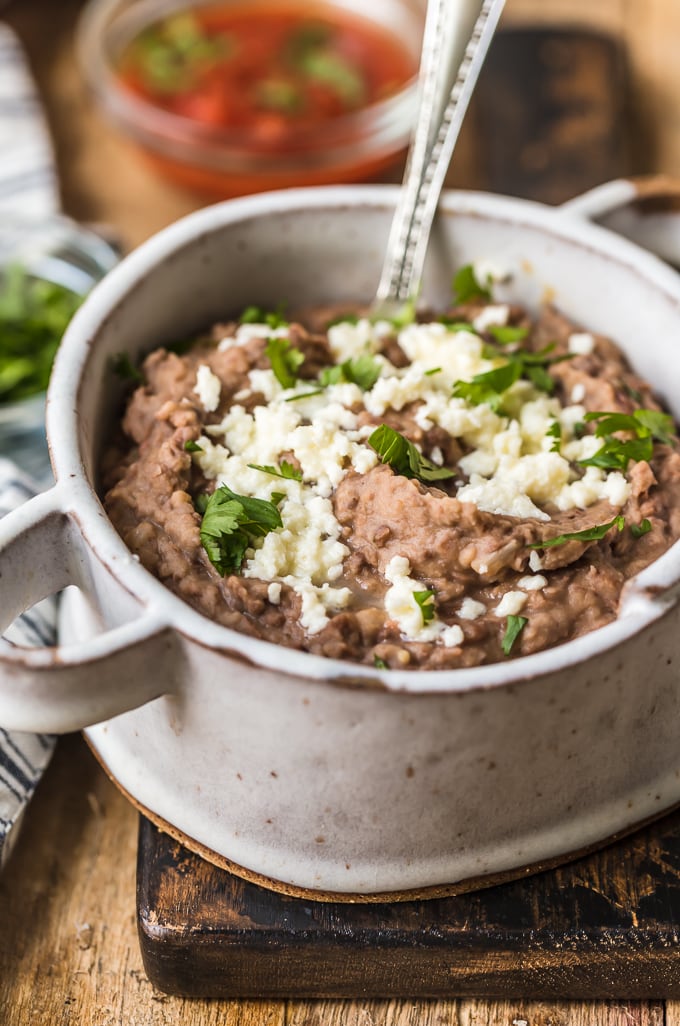 Refried beans in a serving bowl topped with cheese and cilantro