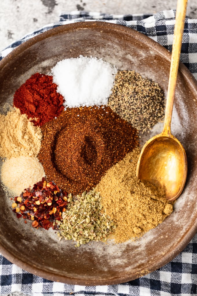 A bowl full of spices with a gold spoon