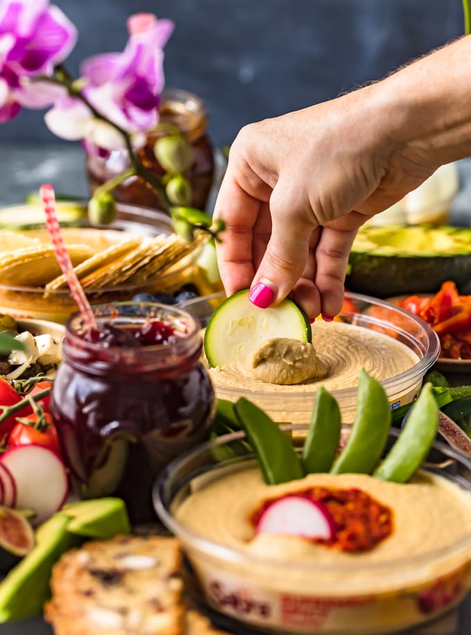 Cucumber being dipped in hummus