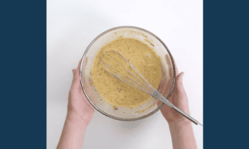 egg custard in a glass bowl with a whisk.