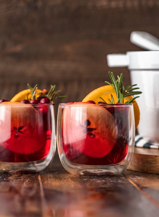 Two glasses of hot apple cider garnished with orange slices