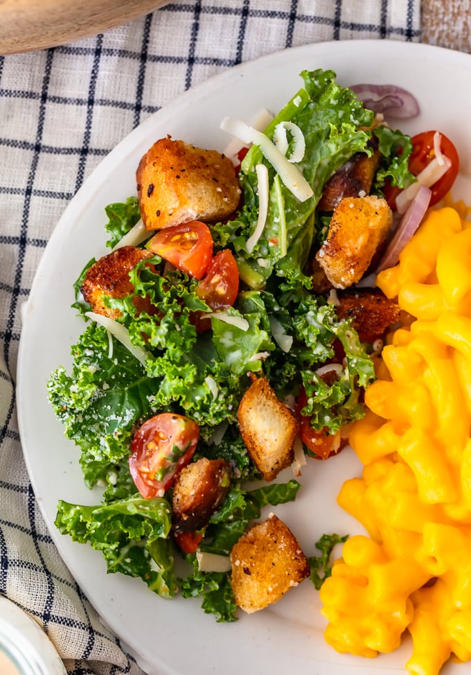 A white plate of kale caesar salad and mac and cheese