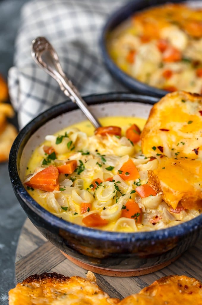 A bowl of macaroni soup topped with a piece of cheesy bread