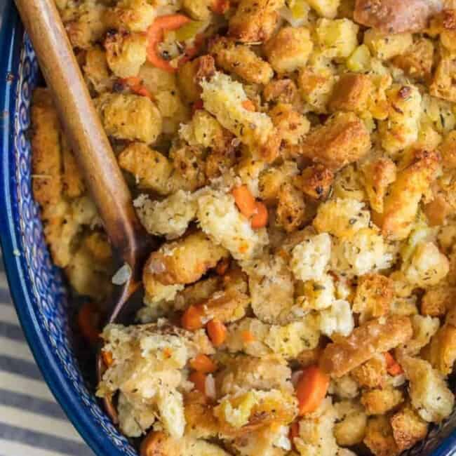 Homemade turkey stuffing in a blue dish with a wooden spoon.