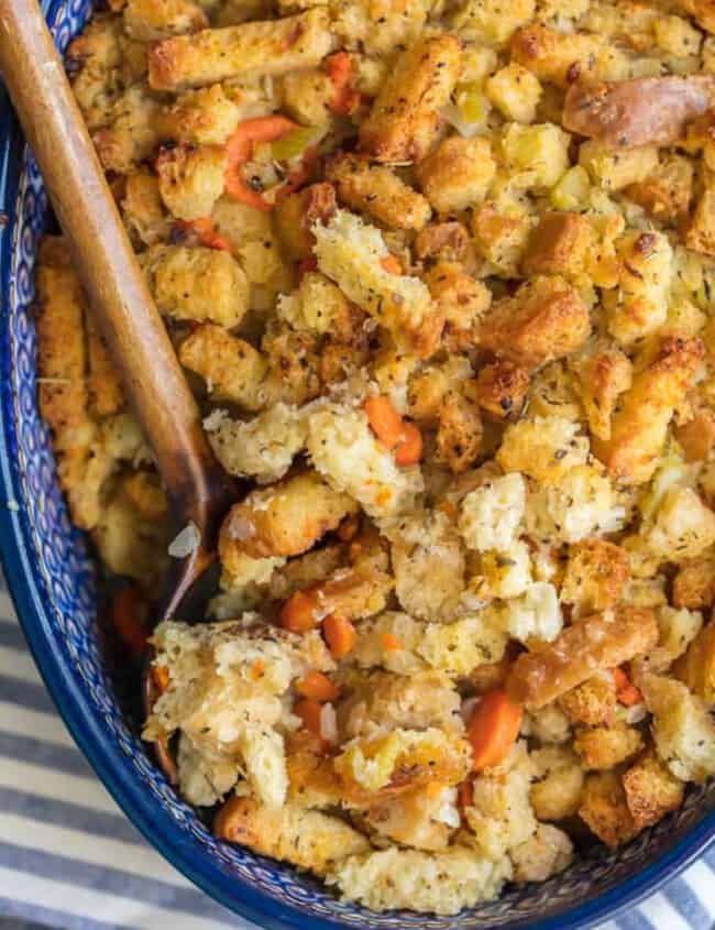 Homemade turkey stuffing in a blue dish with a wooden spoon.