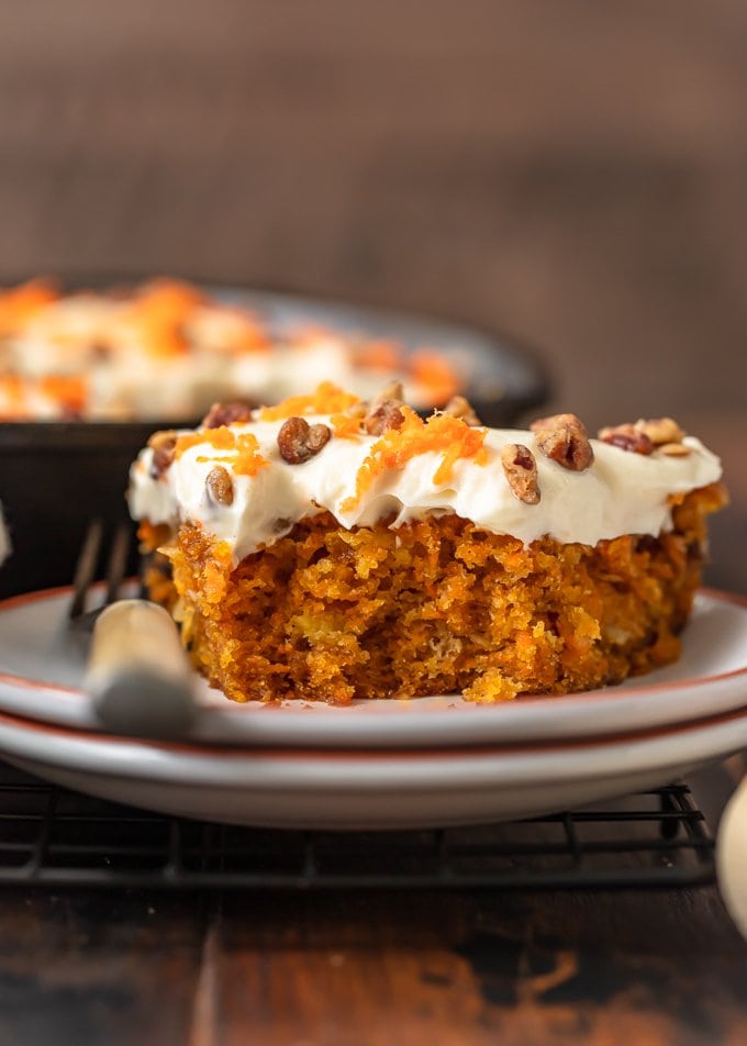 a slice of carrot cake on a small plate, with a bite taken out of it