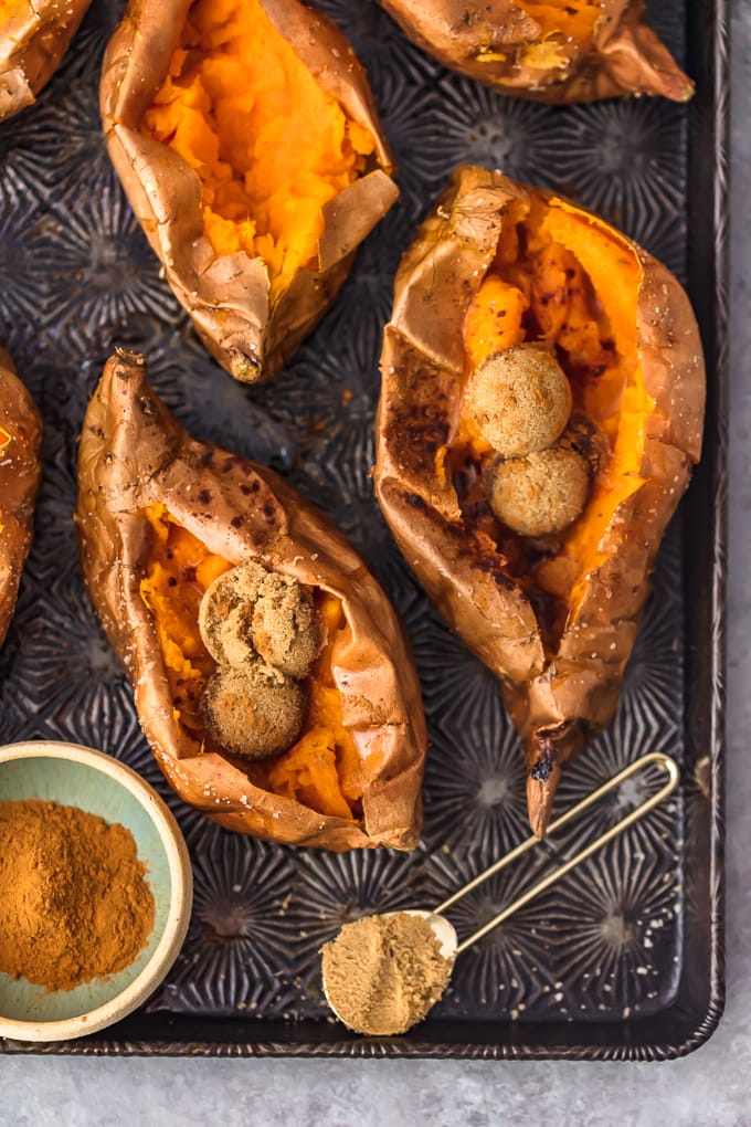 baked sweet potatoes on a baking tray, filled with brown sugar and cinnamon