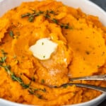 Savory mashed sweet potatoes with sprigs of thyme.