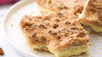 a bitten pecan pie bar on a white plate.