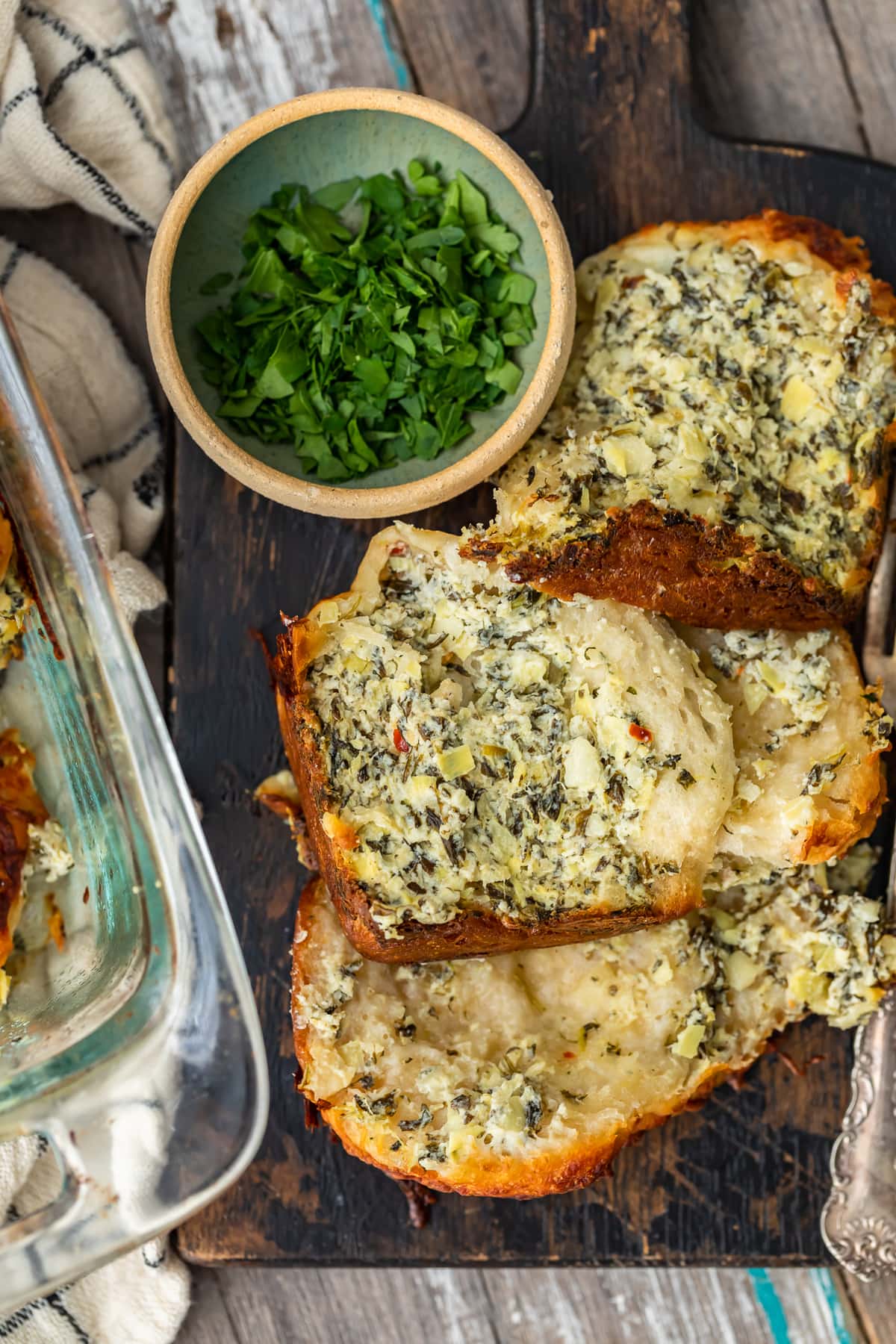 pieces of spinach artichoke dip pull apart bread stacked on a wood serving board