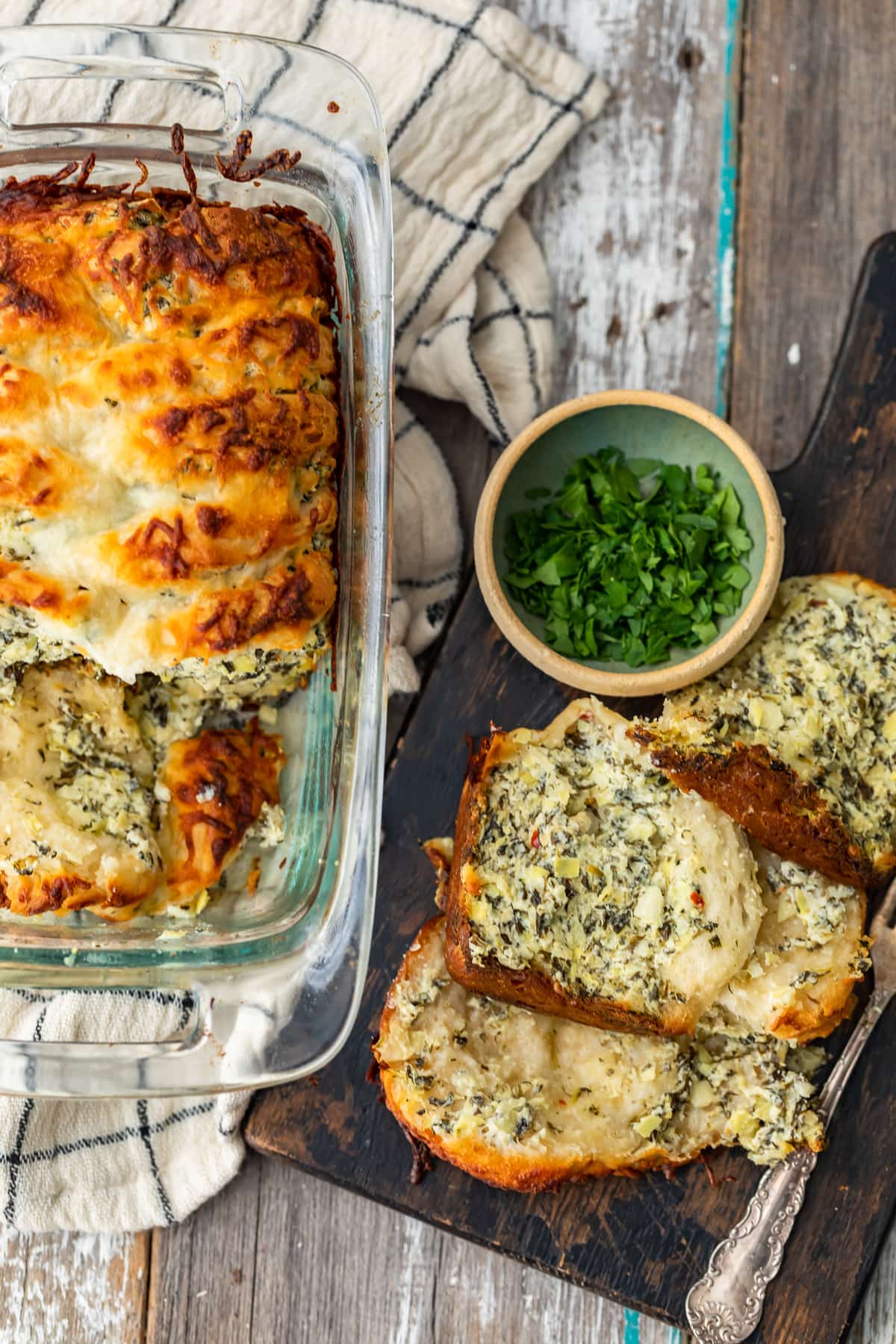 a loaf pan next to pieces of spinach artichoke bread