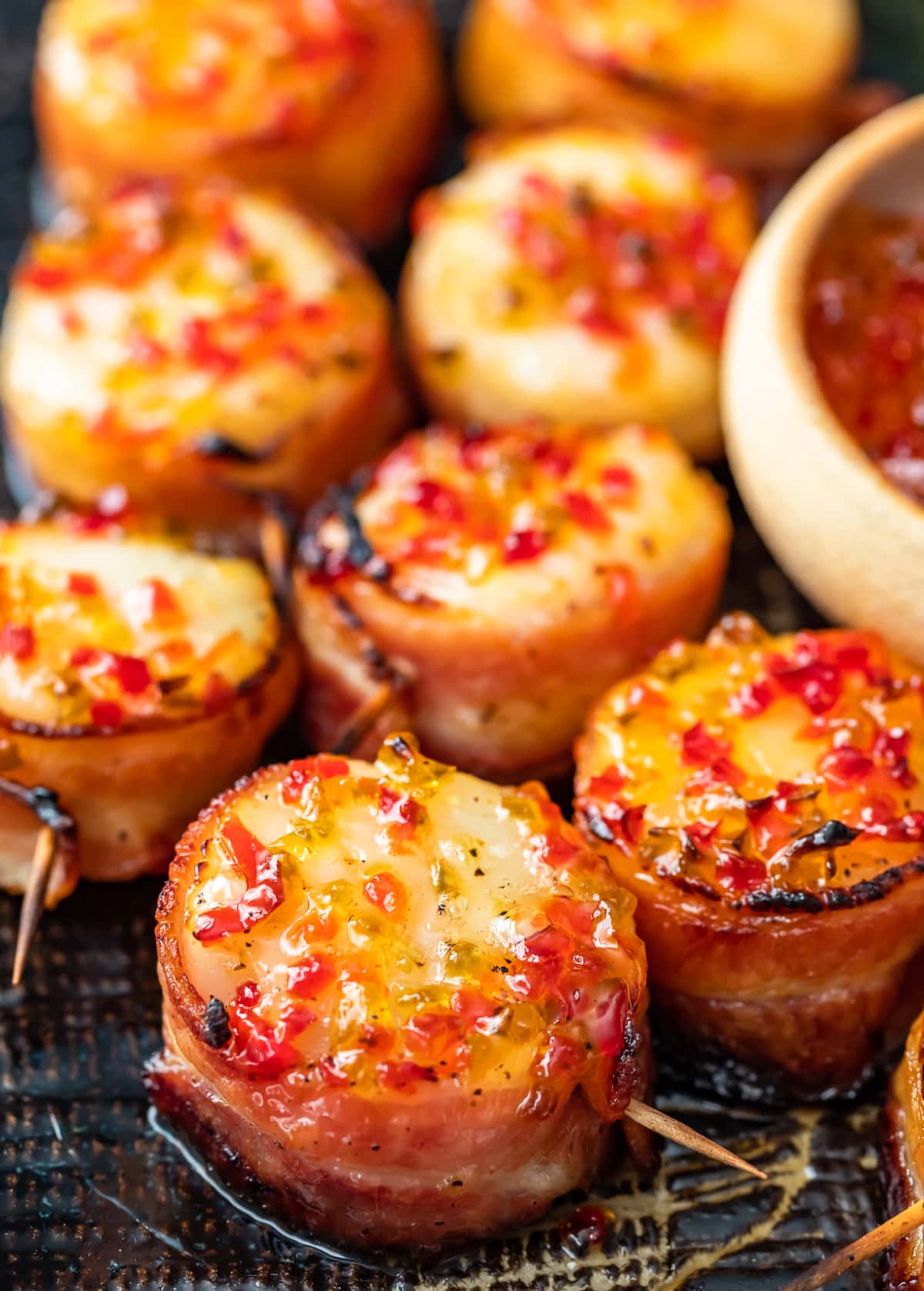 Bacon-wrapped scallops served on a wooden board.