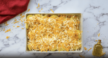 Cheesy sausage and potato casserole in a white dish.