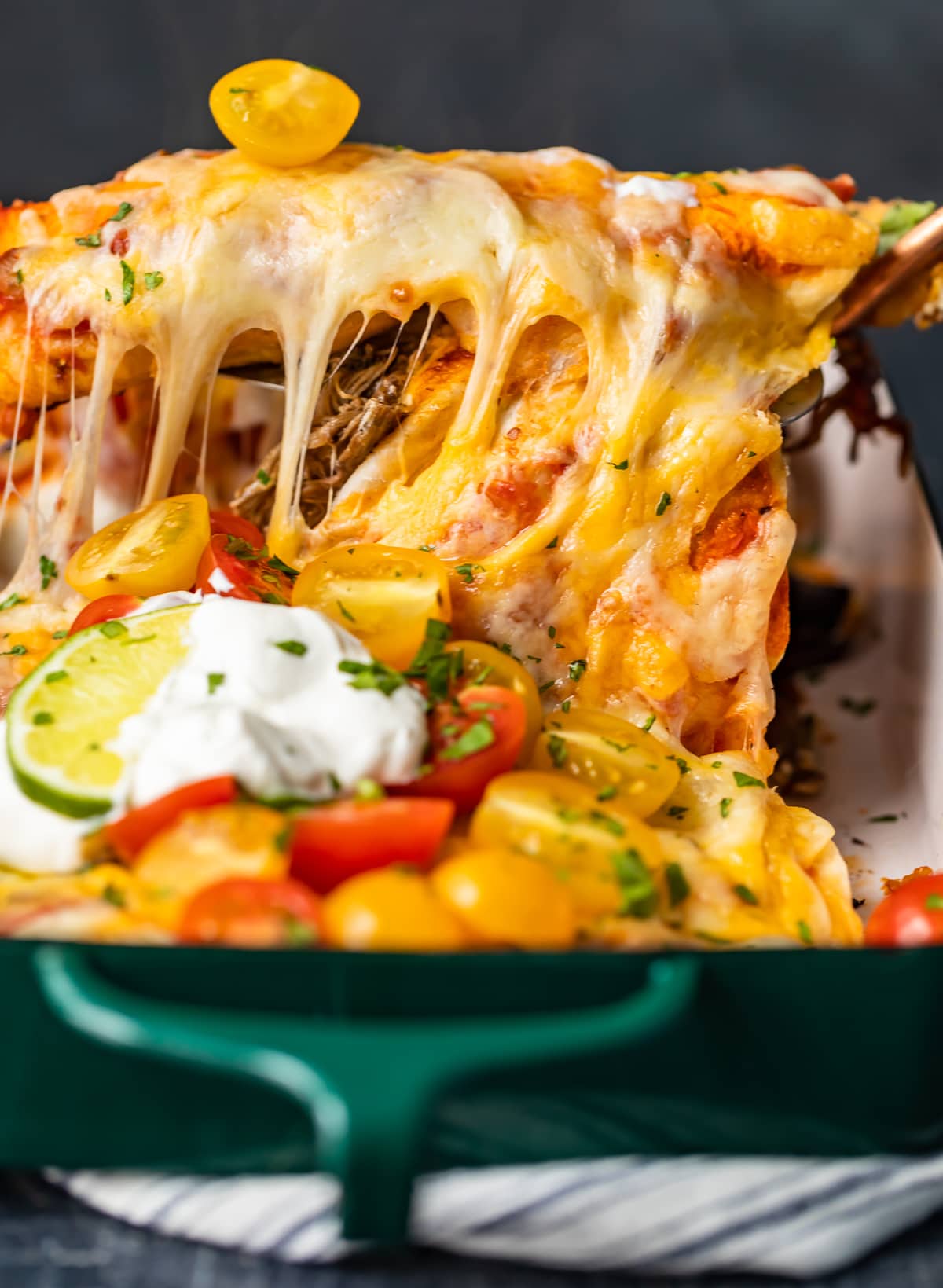 cheesy beef enchiladas in a green casserole dish