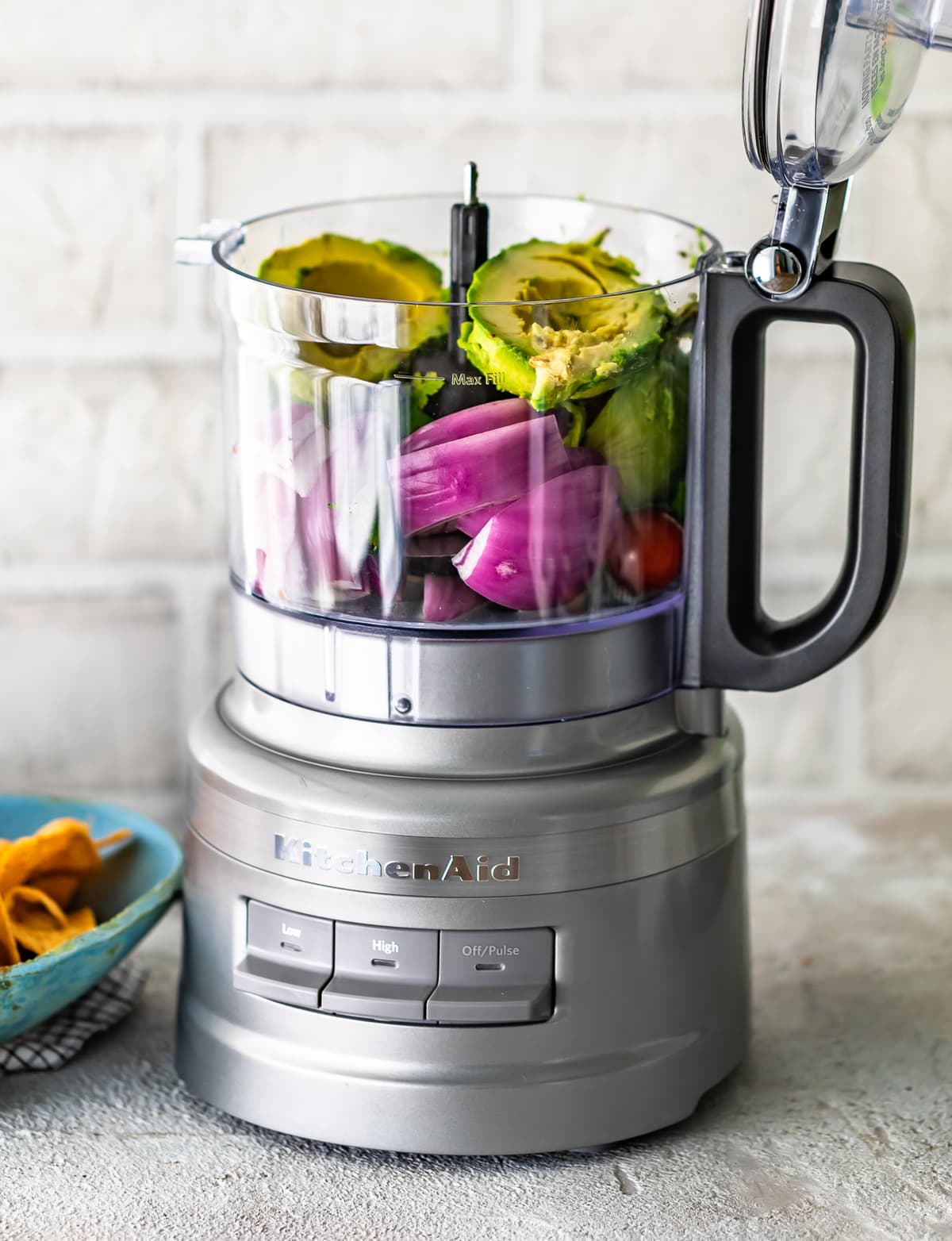 food processor filled with guacamole ingredients