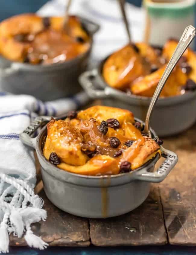 A dish of apple bread pudding with raisins on a wooden board, accompanied by a refreshing St. Patrick's Day punch.