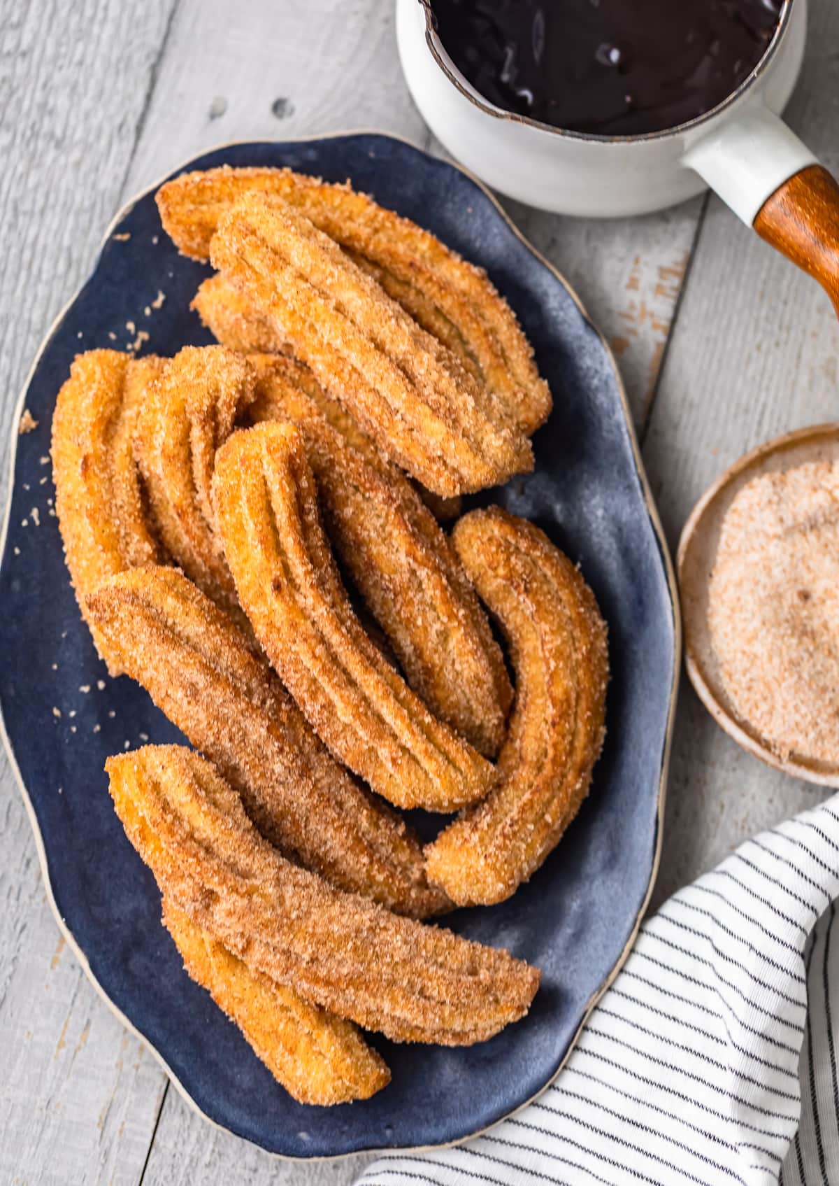 easy churros rolled in cinnamon sugar on a platter