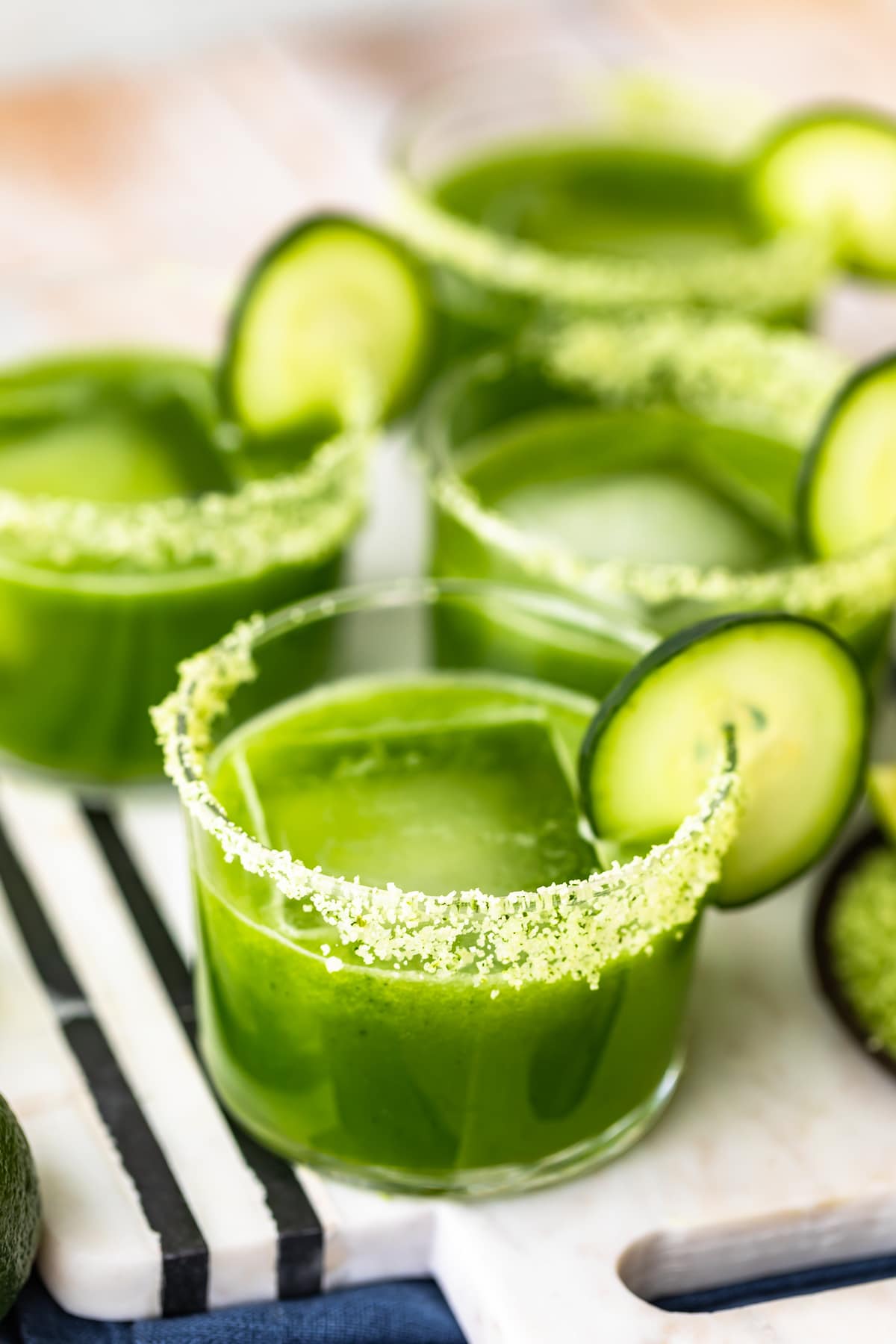 glasses full of cucumber margaritas garnished with cilantro salt and cucumber slices