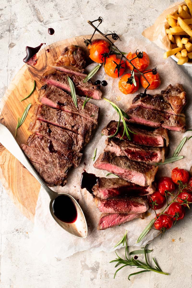 sliced strips steaks on a cutting board with tomatoes.