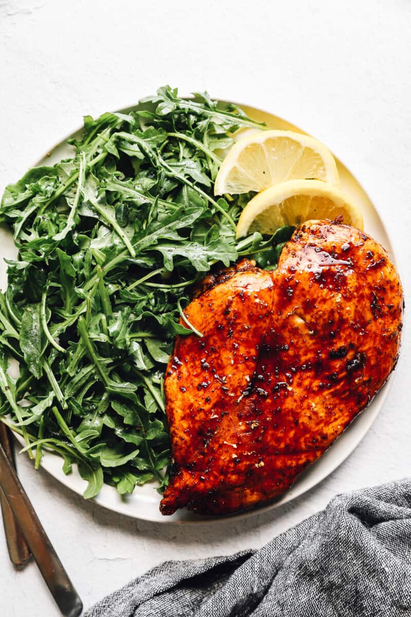 balsamic chicken on white plate with simple salad and lemon