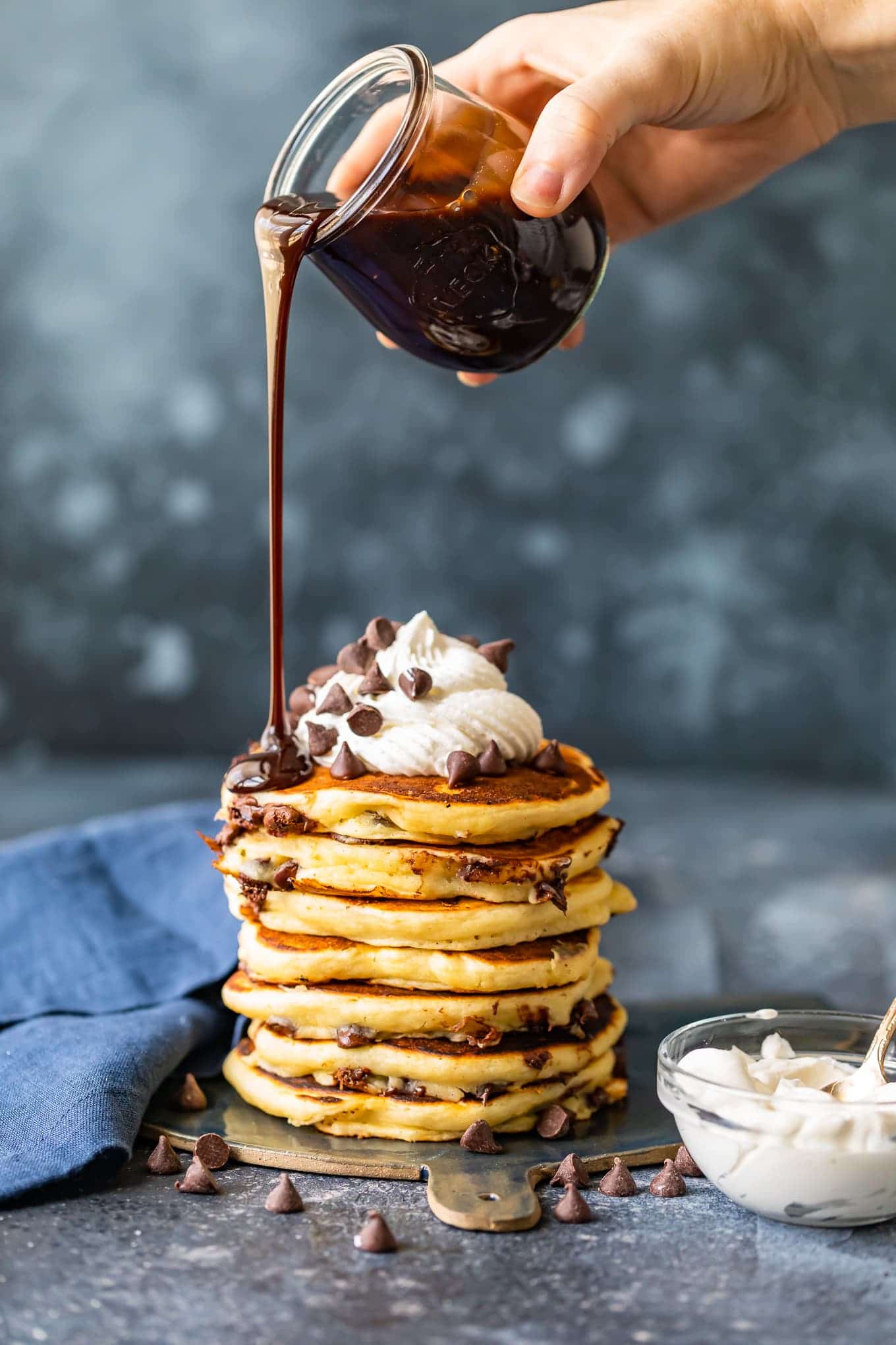 chocolate sauce being poured over pancakes