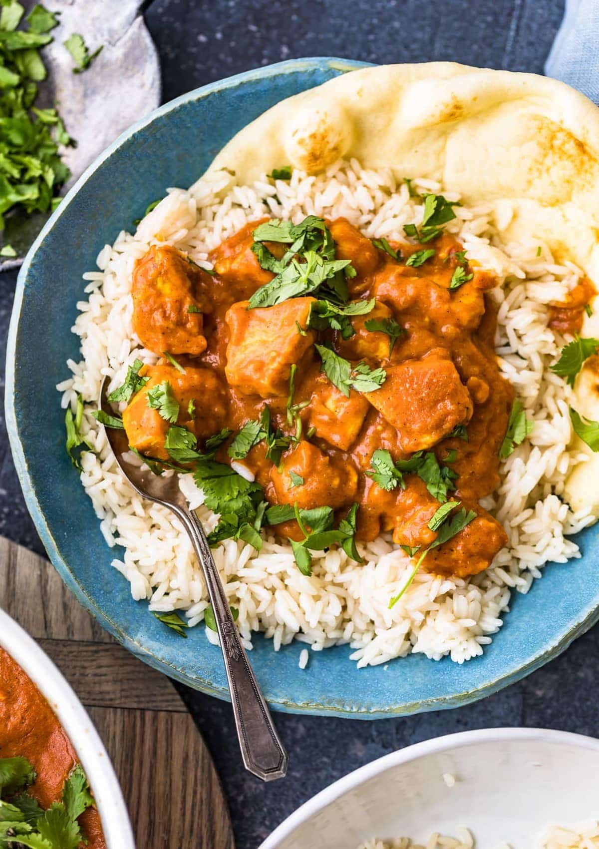 chicken curry on a bed of rice and bread on a blue plate