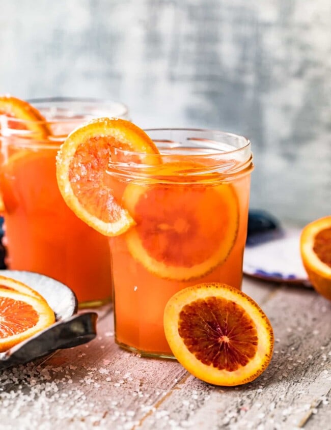 blood orange paloma in glass garnished with oranges