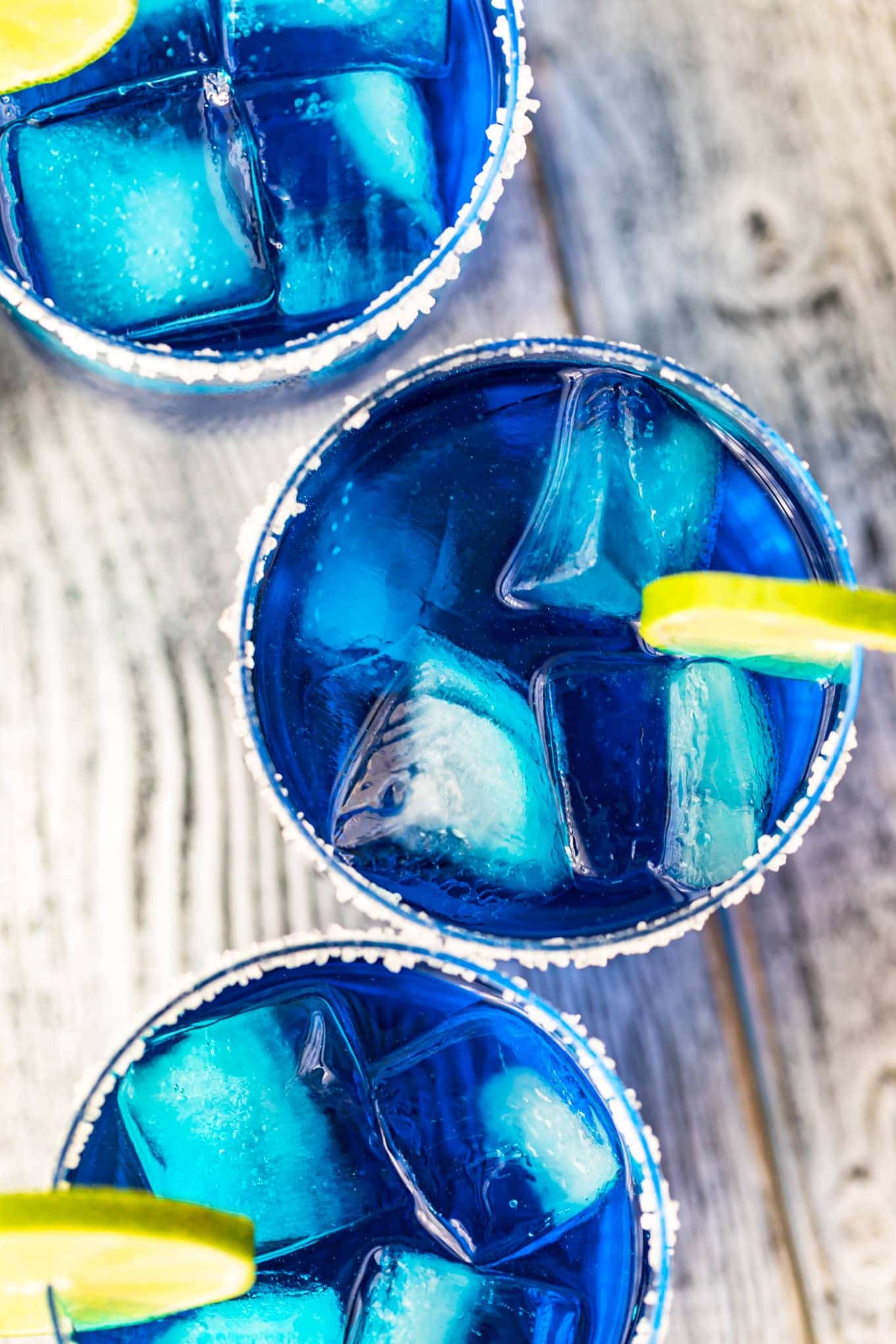 Blue maragaritas in glass with ice and lime slices