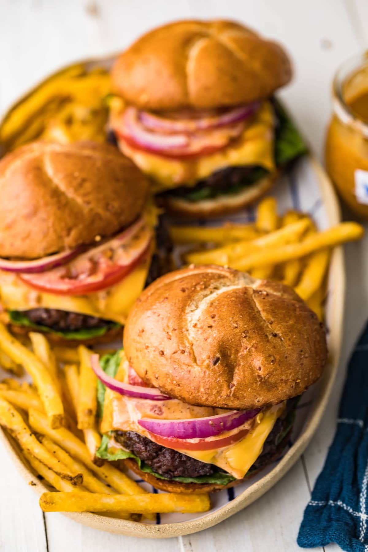 Three cheeseburgers and French fries on a serving platter.