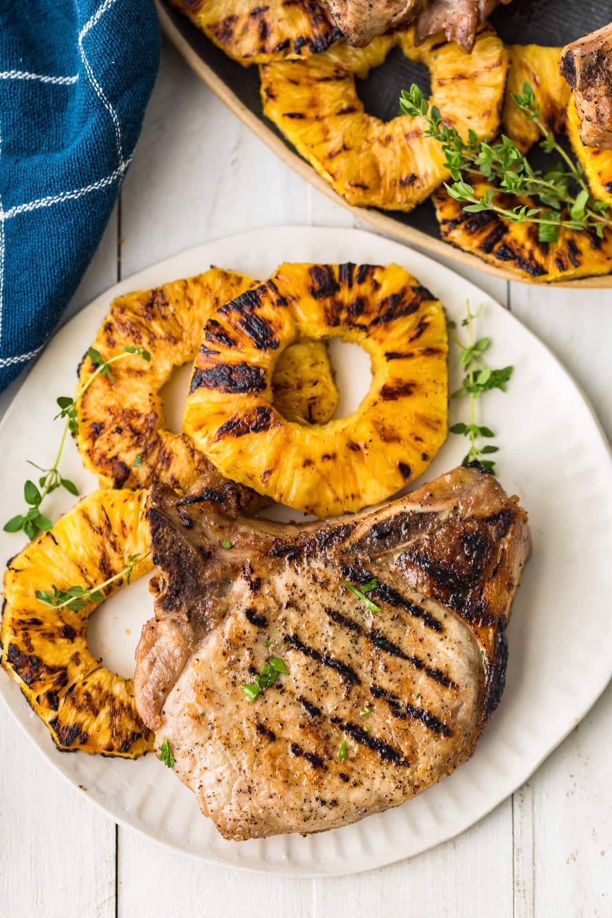 A chop served with pineapple rings on a white pate