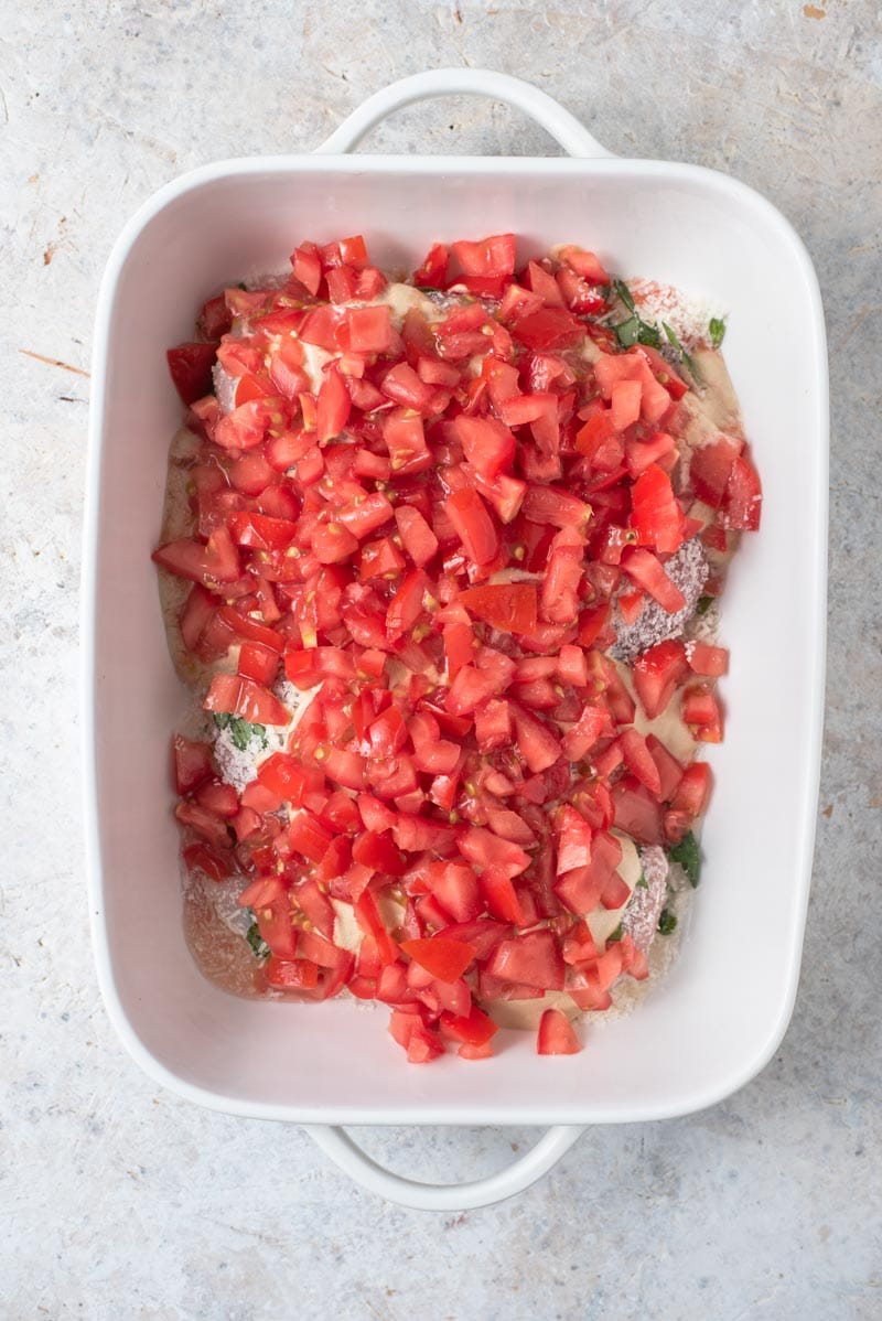 An overhead shot of bruschetta chicken in a casserole dish with fresh chopped tomatoes on top