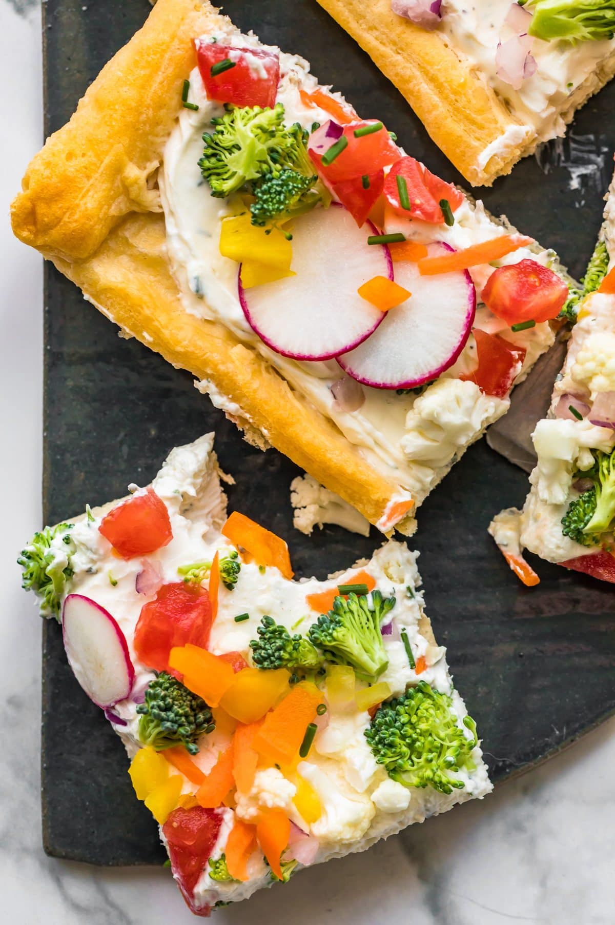 Veggie pizza squares arranged on black slate