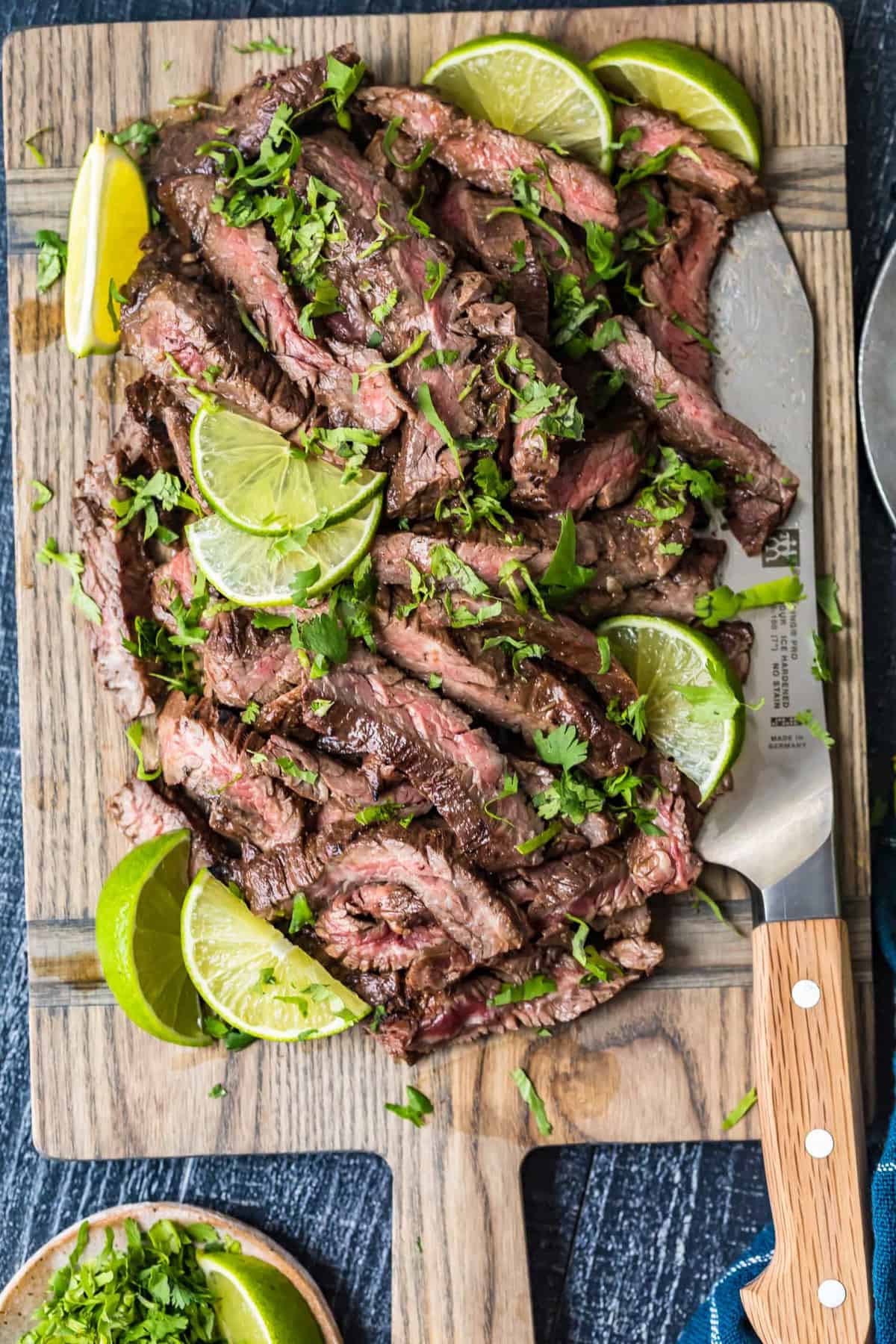 Top down shot of Carne Asada Steak on a board with lime slices