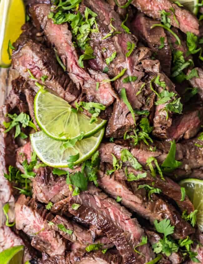 top shot of carne asada steak with sliced lime and cilantro