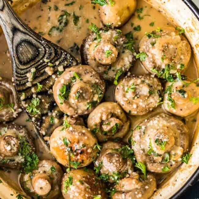 Creamy garlic mushrooms sautéed in a skillet with a spoon.