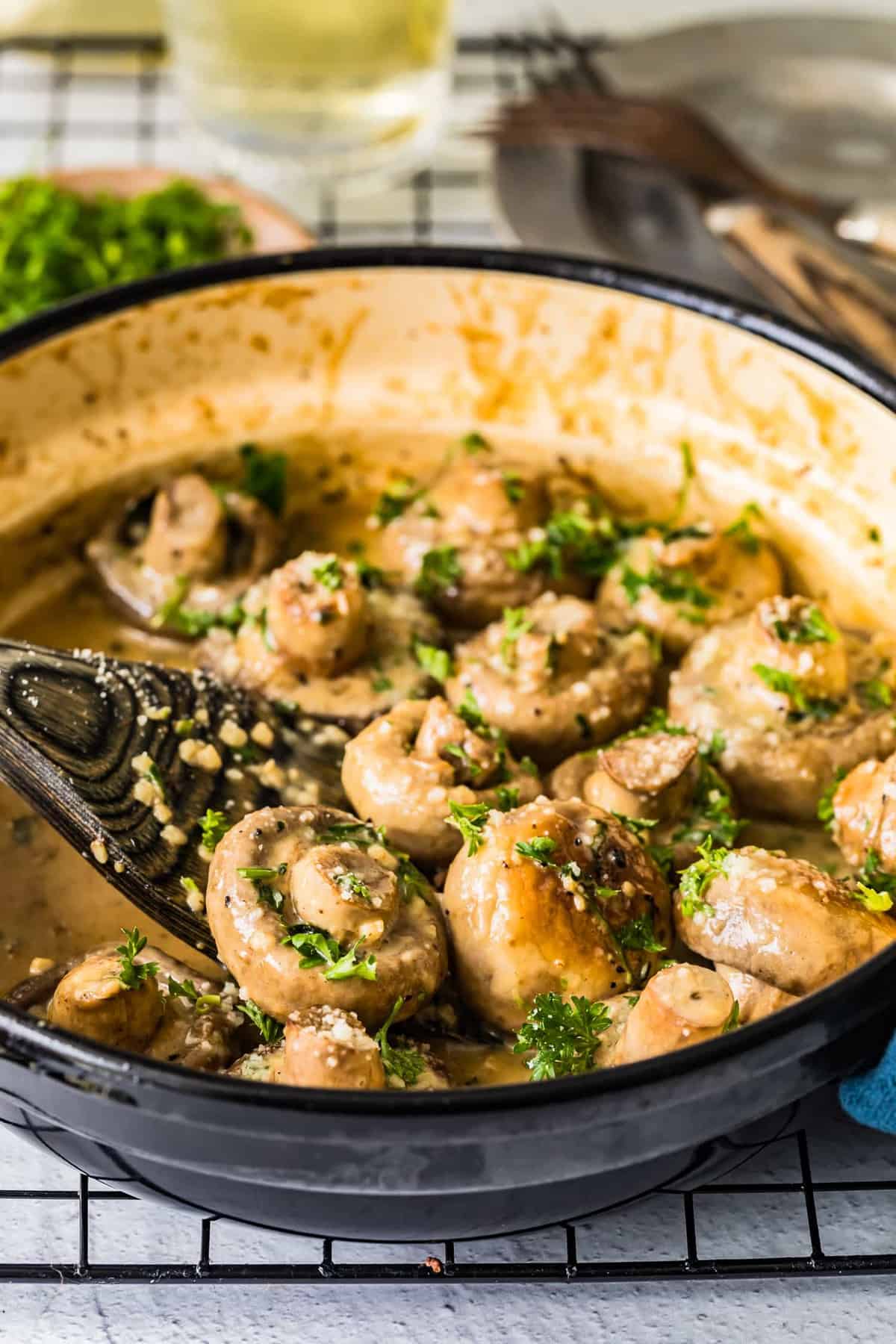 creamy garlic mushrooms being stirred with a wooden spoon