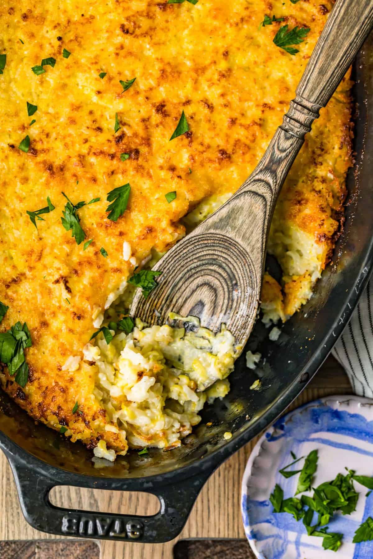 Baked zucchini gratin in a black dish with a wooden spoon