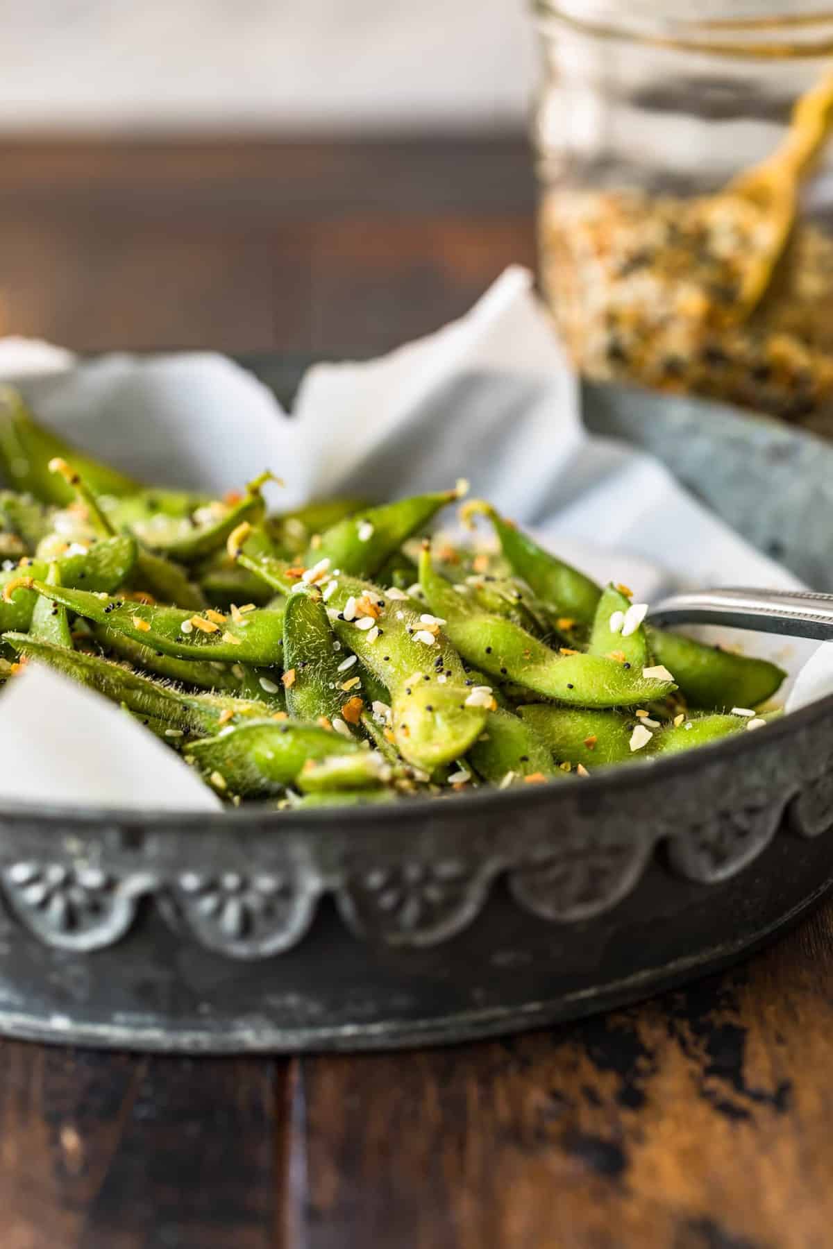 A side view of the edamame sitting in a silver dish with a spoon