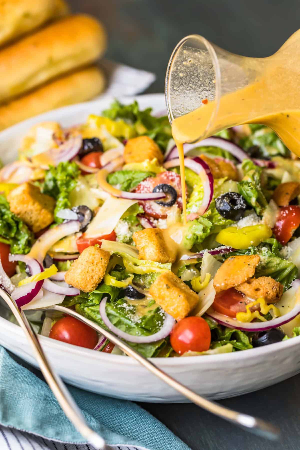 Italian dressing being poured over a salad