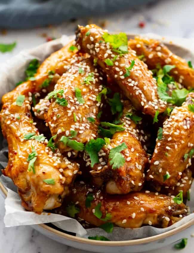 honey glazed chicken wings topped with sesame seeds and cilantro in a bowl