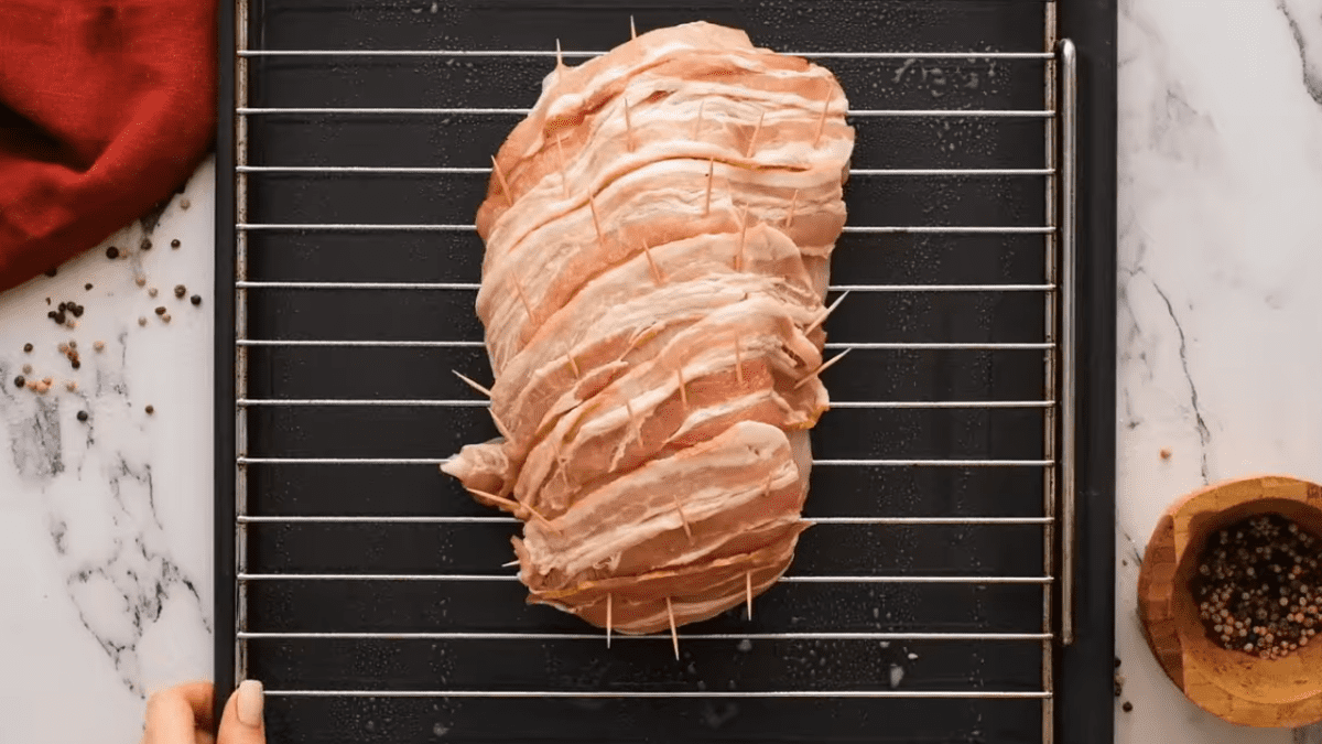 bacon wrapped turkey breast with toothpicks sitting on a rack before roasting