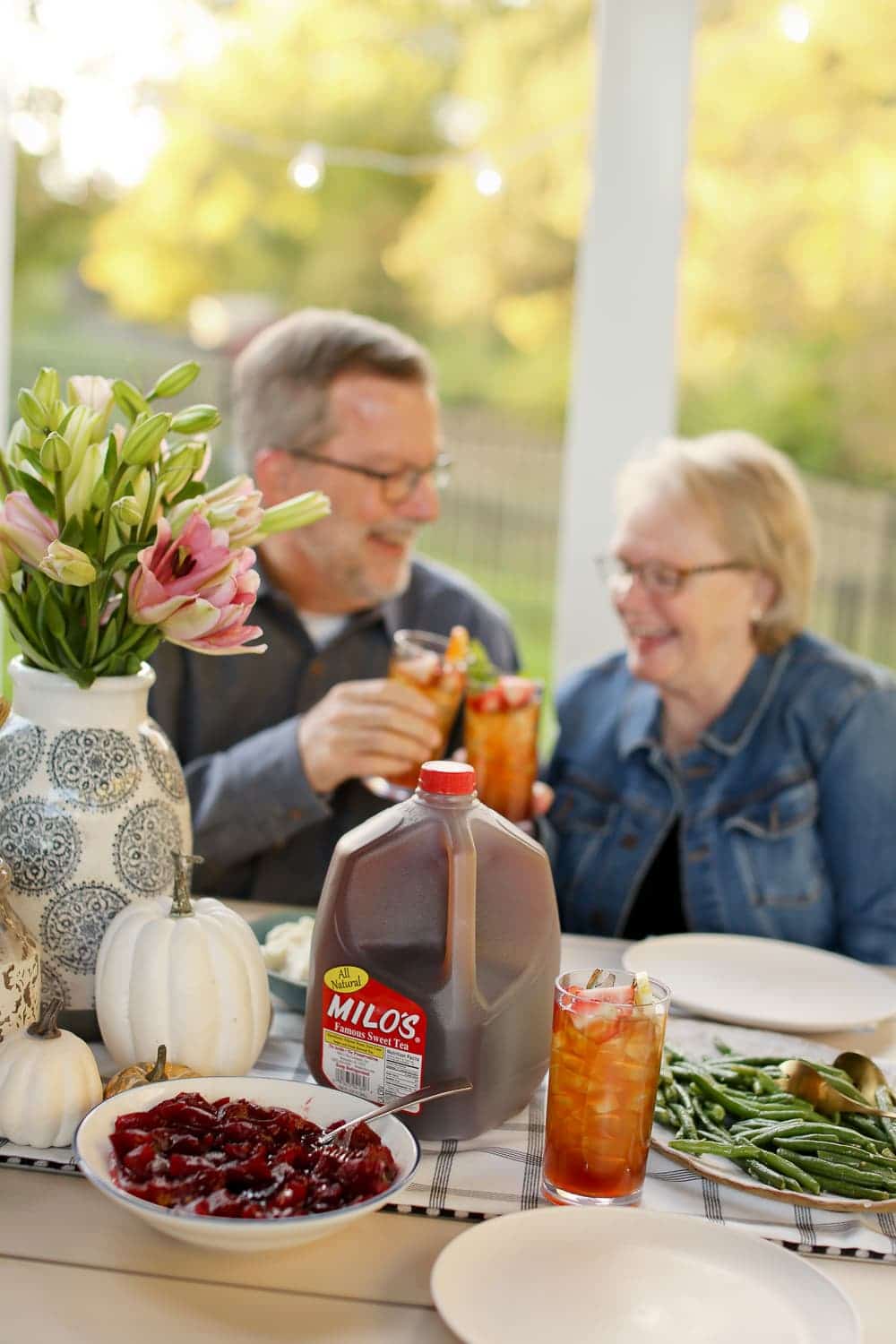 An older couple cheersing their glasses with Milo's Sweet Tea in front of them