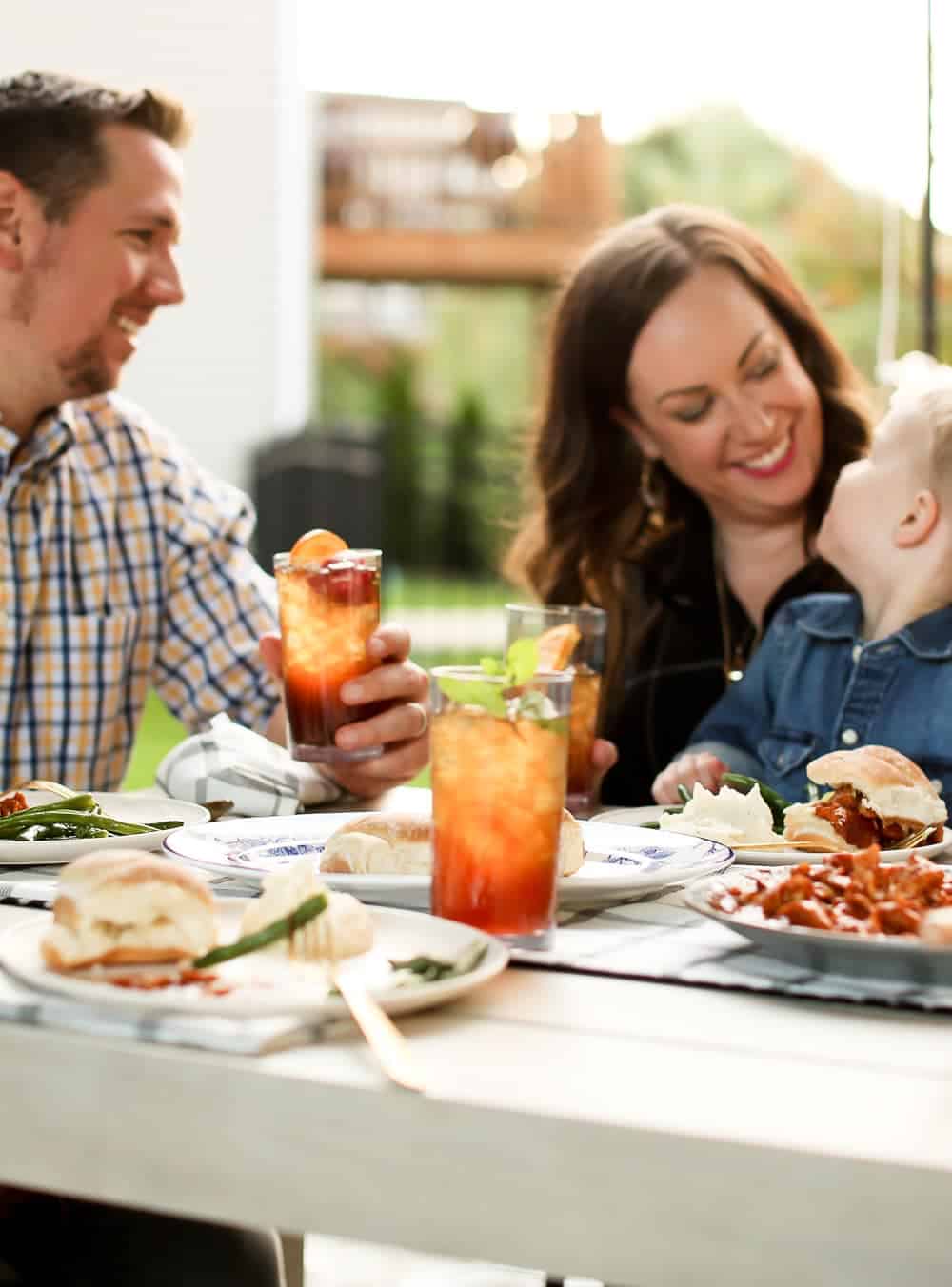 A family of three sitting at a dinner table smiling at each other