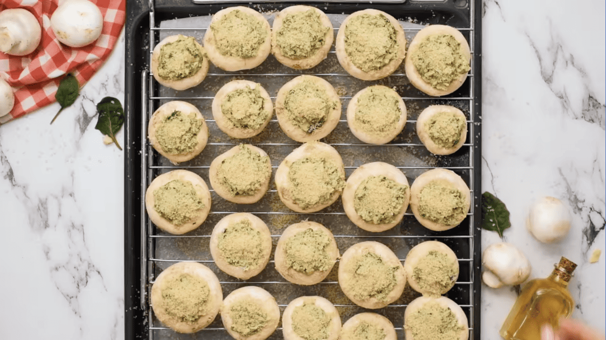 breadcrumbs on top of spinach stuffed mushrooms on a rack.