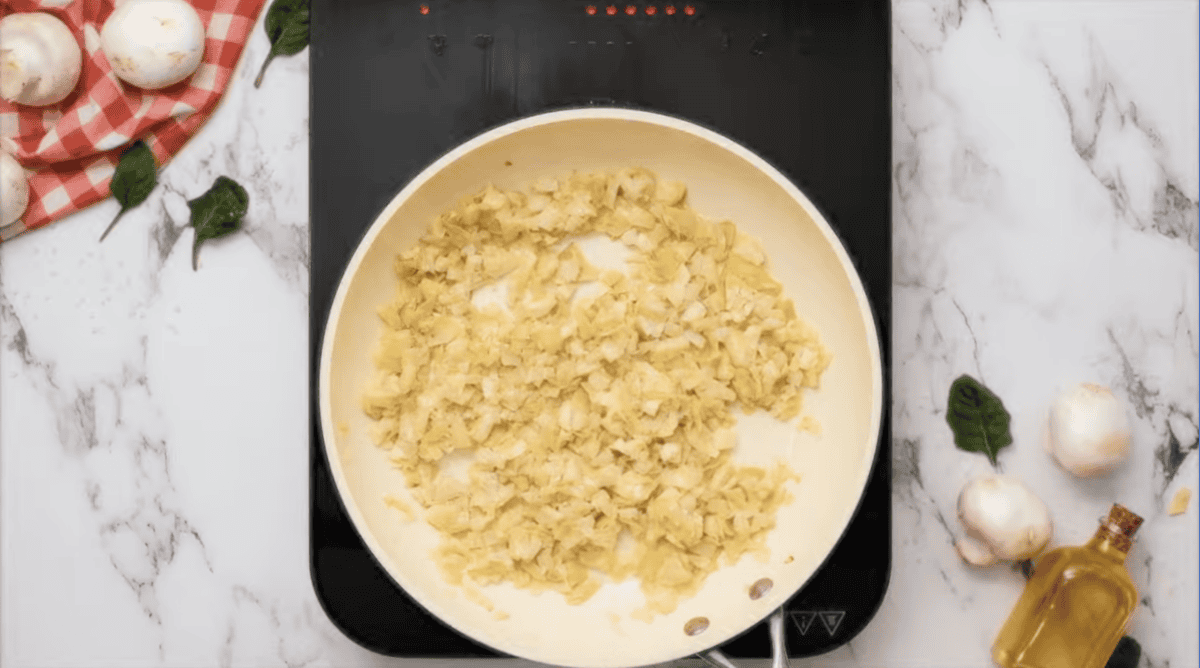 chopped artichoke hearts cooking in oil.