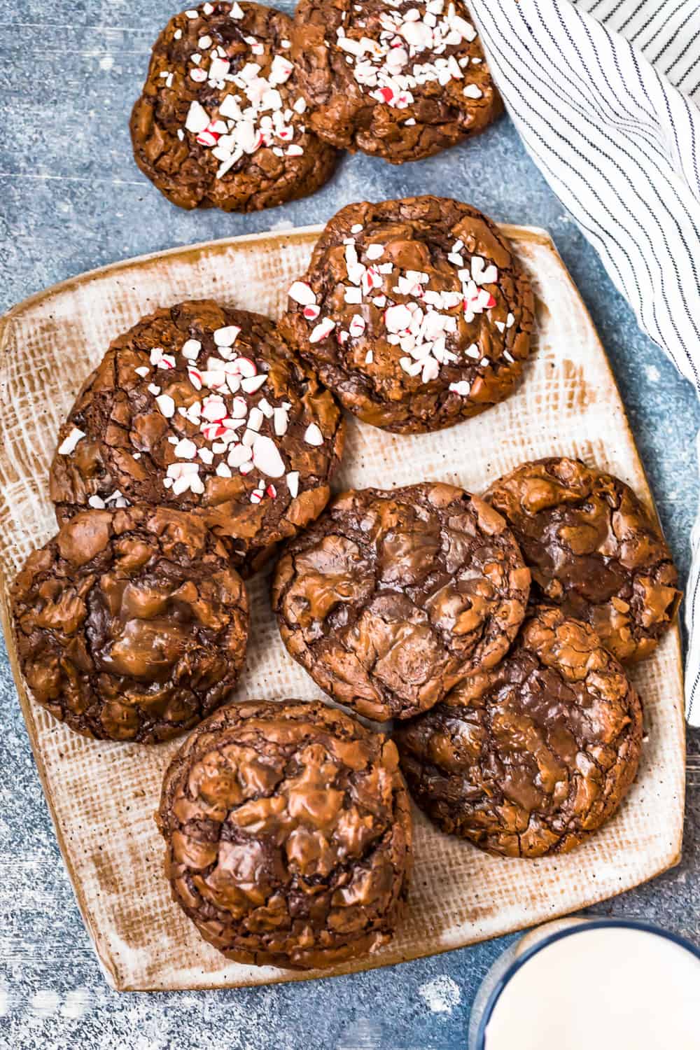 a mix of fudgy brownie cookies on a plate, some cookies with crushed peppermint candy on top