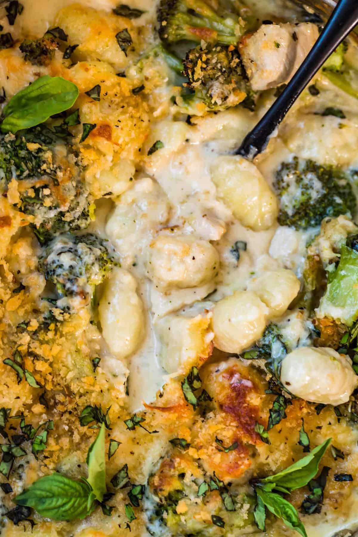 Close up view of Chicken Alfredo Gnocchi Bake with a black spoon